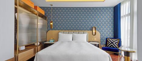 A hotel room with a large bed, a wardrobe, a bedside table, a chair, and a nightstand.