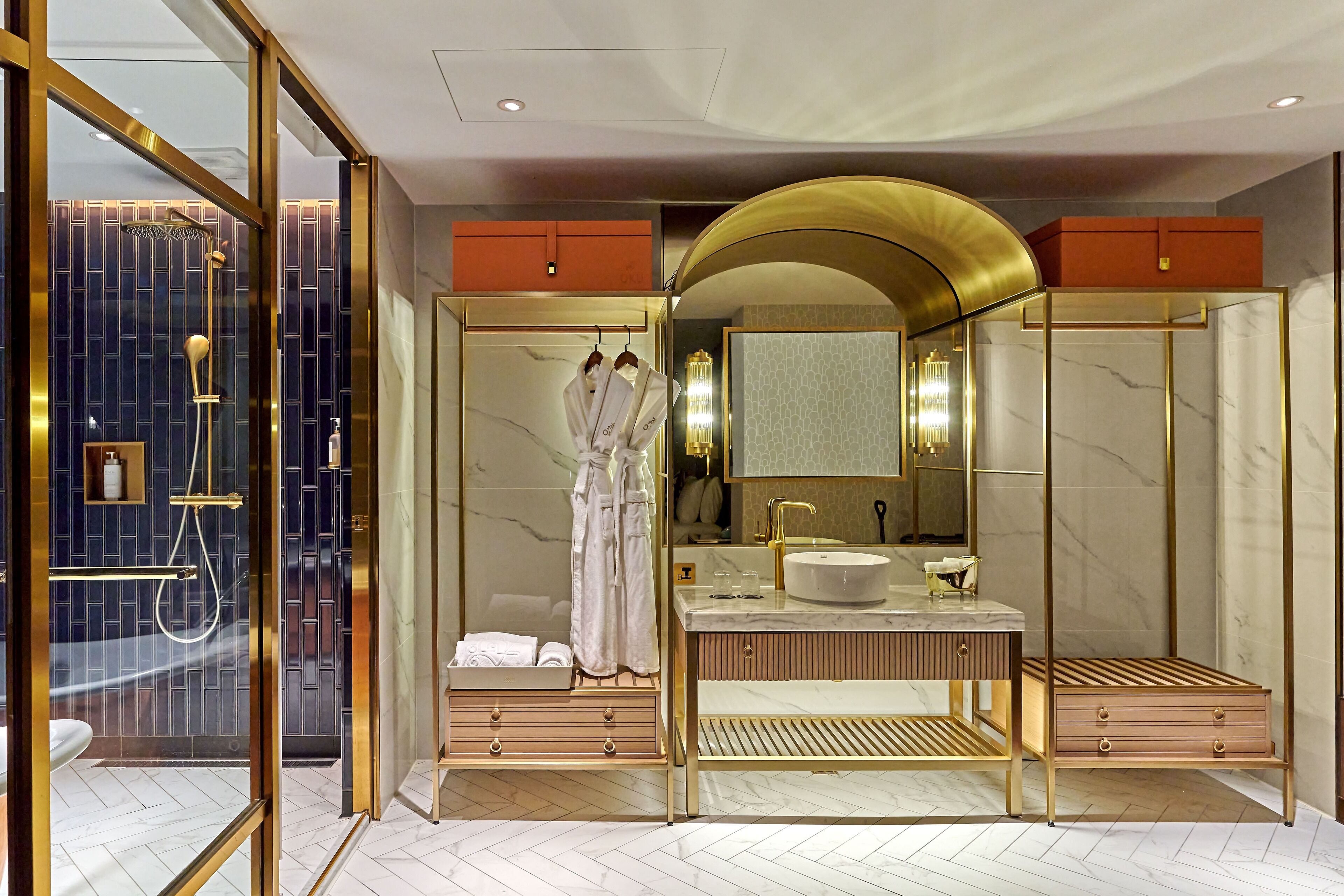 Un baño lujoso con un espejo grande, detalles dorados y un diseño moderno.