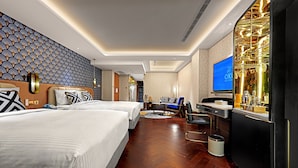 Habitación de hotel con dos camas, un escritorio, televisión y minibar.