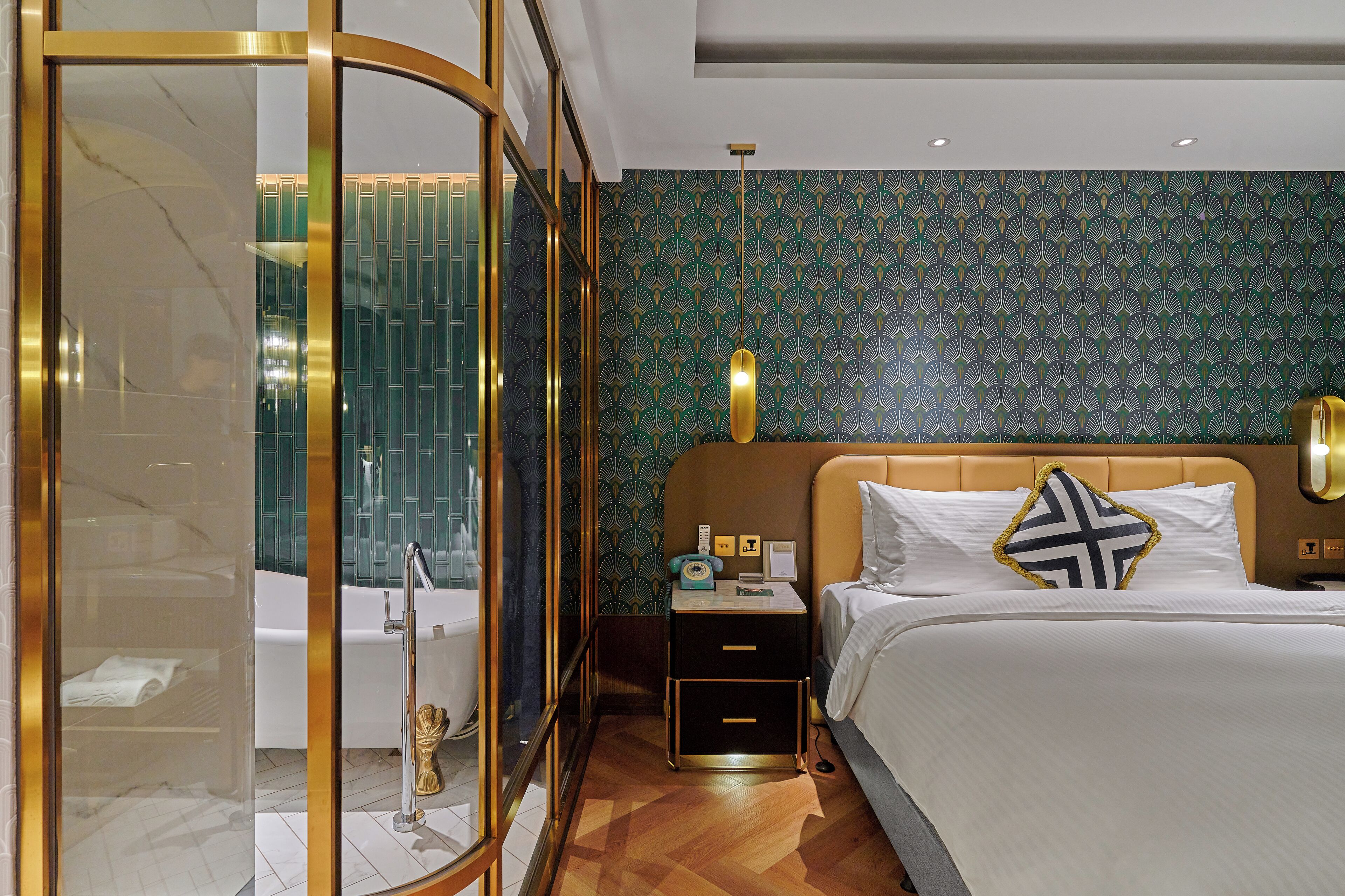 A hotel room with a bed, a nightstand, a mirror, a shower, and a patterned wall.