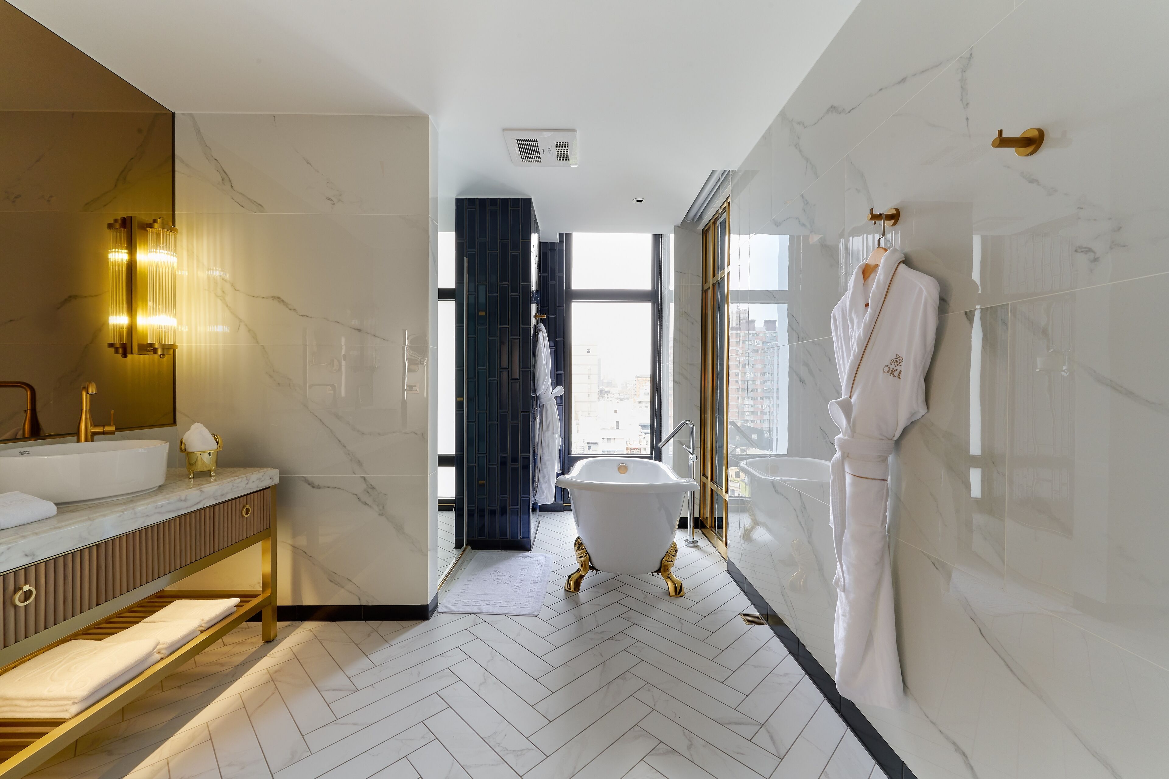 A modern bathroom with a freestanding bathtub, a large mirror, and a vanity with a gold finish.