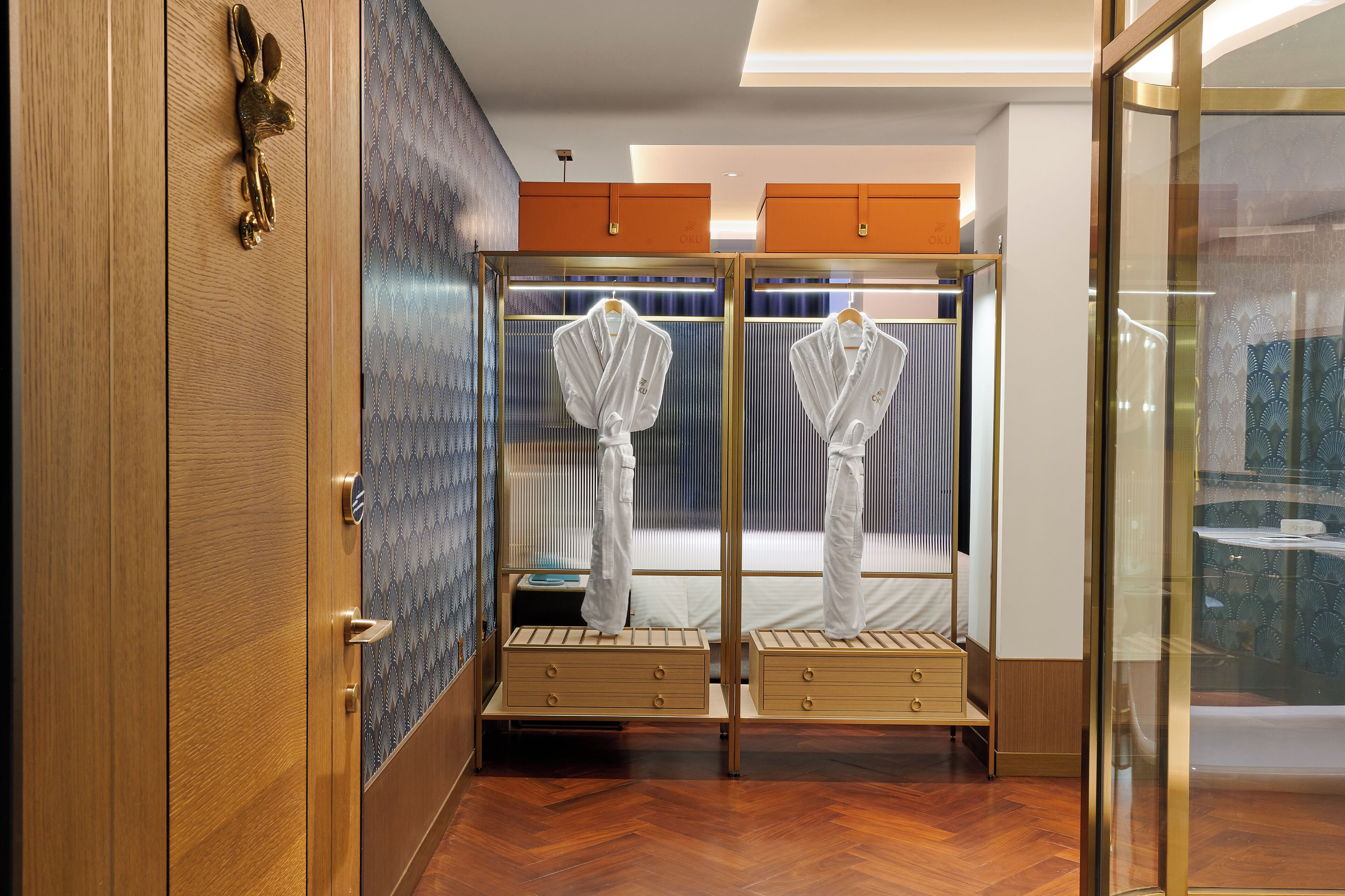 A hotel room with a wooden wardrobe, a mirror, and two bedside tables with drawers.