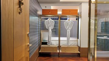 A hotel room with a wooden wardrobe, a mirror, and two bedside tables with drawers.