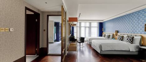 Habitación de hotel con una cama grande, un escritorio y una silla. Hay una puerta que conduce a otra habitación.