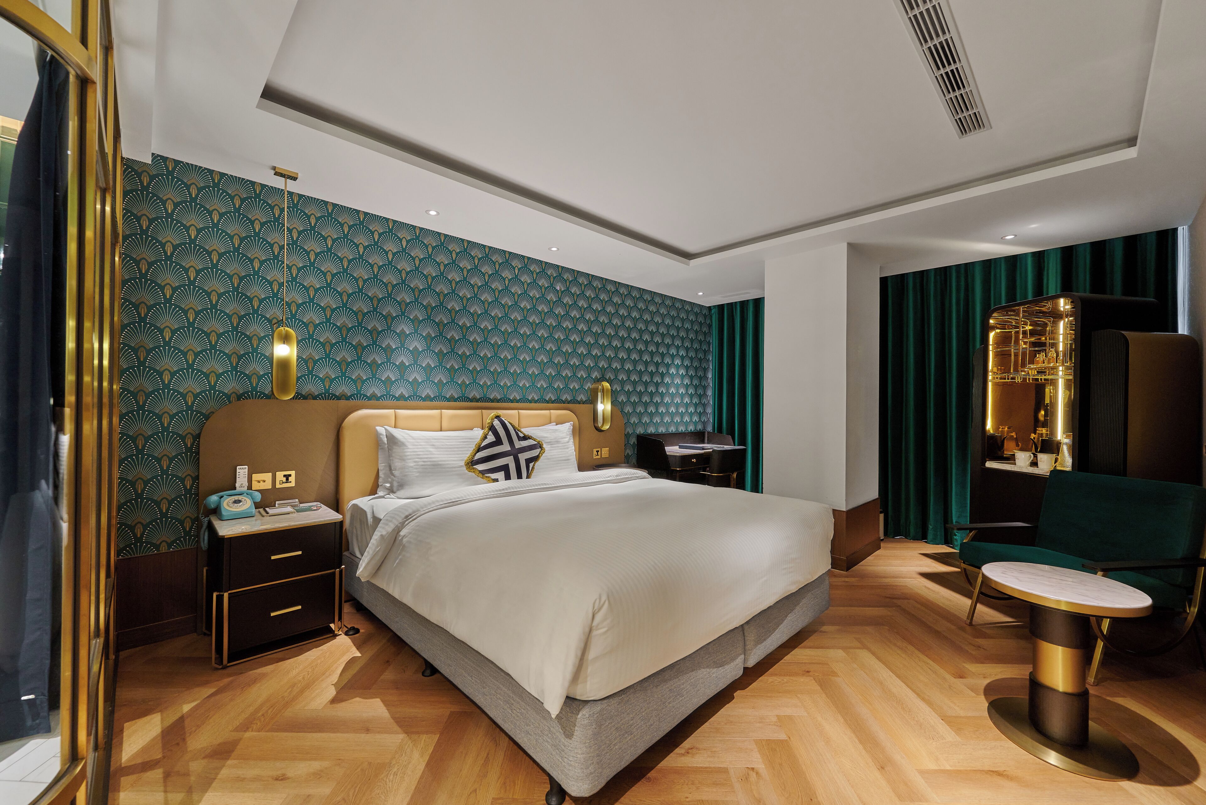 A modern hotel room with a bed, bedside tables, a desk, and a chair.