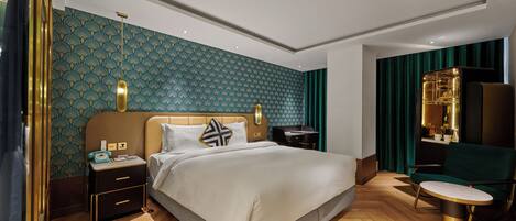 A modern hotel room with a bed, bedside tables, a desk, and a chair.