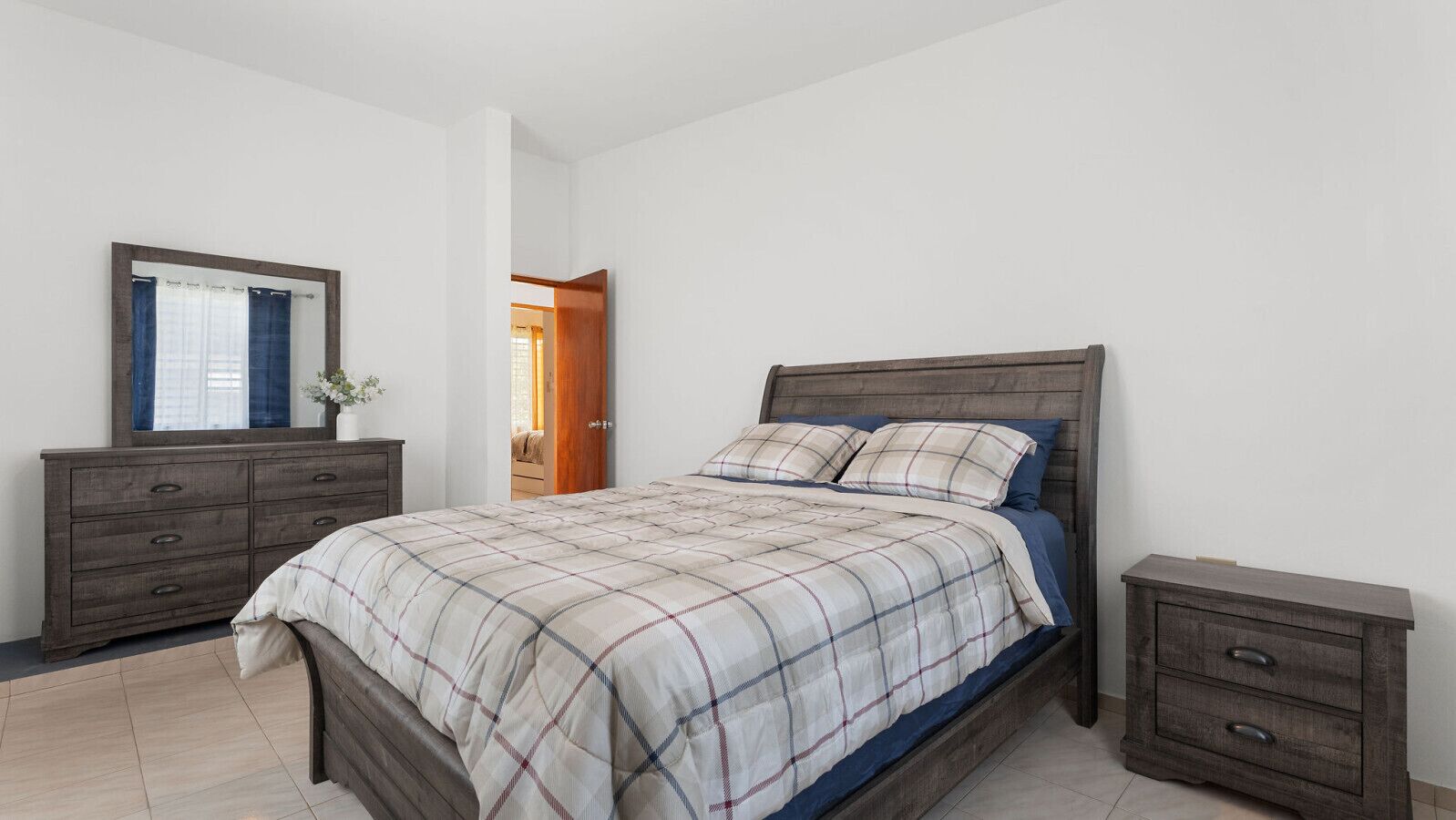 Een slaapkamer met een bed, een dressoir en een nachtkastje.