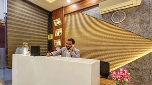 A reception desk with a check-out sign, a clock, and a vase of flowers. - Hotel Church View (New Delhi)