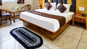 A hotel room with a bed, a desk, a chair, a ceiling fan, and a view of the sky. - Hotel Church View (New Delhi)