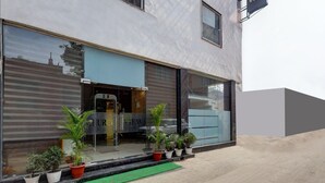 A modern building with a large glass facade, a visible entrance, and potted plants on the ground level. - Hotel Church View (New Delhi)