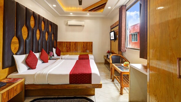 A hotel room with a large bed, a ceiling fan, a TV, and a window with curtains. - Hotel Church View (New Delhi)