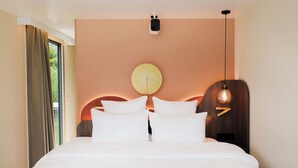 Habitación de hotel moderna con una cama grande, un adorno circular en la pared, una lámpara de techo y una ventana con cortinas.