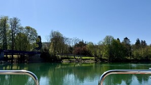 Un río tranquilo con un puente al fondo y barandillas metálicas en primer plano.