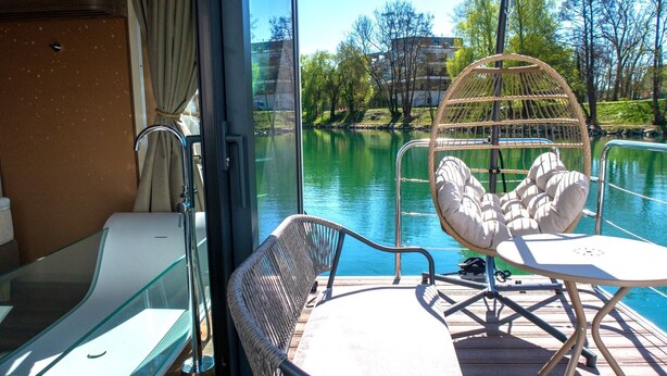 A deck with a glass partition, a wicker chair, and a small table. - L'Escale Royale La Ferté-sous-Jouarre (La Ferté-sous-Jouarre)