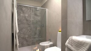 Un baño moderno con cabina de ducha de vidrio, un inodoro y un lavabo.