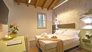Un dormitorio con cama, mesita de noche, silla y escritorio con planta y velas.