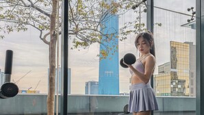A person exercising with a dumbbell in an outdoor urban setting with buildings and a tree in the background. - Dorsett Kuala Lumpur by Five Senses (Kuala Lumpur)