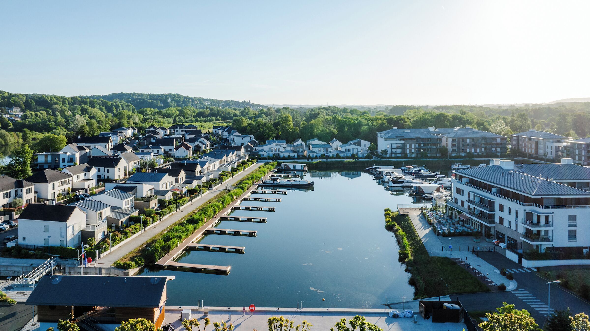 Un quartier résidentiel situé au bord de la rivière, avec des maisons modernes, un port de plaisance et un restaurant.