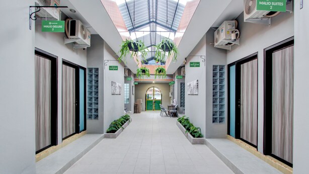 A hotel corridor with a skylight, air conditioning units, potted plants, and directional signs. - Hotel O Yogyakarta near Jalan Malioboro formerly Malio Inn (Yogyakarta)