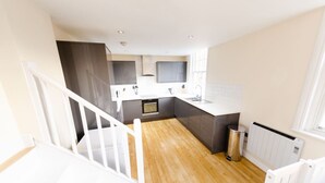 A modern kitchen with a central island, a built-in oven, and a stainless steel sink. - Charlotte House: Prime Location Urban Nest – 2BED 2BATH (Ipswich)