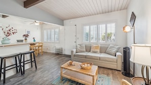 A spacious living room with a sofa, coffee table, and a dining area with chairs and a small table. - Beautiful 1 Bed Beach Condo #224 1 Bedroom Condo by Sunset Shores Condominiums (Carpinteria)