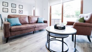 Un salon moderne avec un canapé en cuir marron, une table basse ronde et un fauteuil marron.