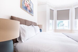 Habitación de hotel con una cama grande, una mesita de noche, una lámpara y un cuadro en la pared.