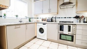 Una cocina moderna con lavadora, horno y electrodomésticos sobre la encimera.