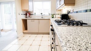 Una cocina moderna con encimera de granito, estufa a gas y muebles color beige.