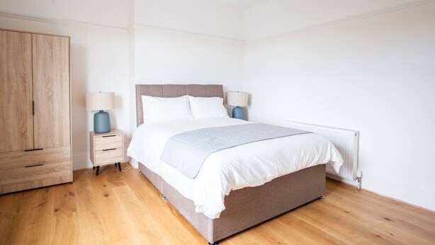 A bedroom with a bed, bedside tables, a wardrobe, and a radiator. - 2BR Seaside Sanctuary in St Leonards on Sea Flat 5 (Hastings)