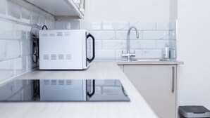 A modern kitchen with a microwave, sink, and stainless steel trash bin. - 2BR Seaside Sanctuary in St Leonards on Sea Flat 5 (Hastings)