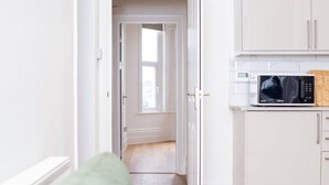 Une cuisine moderne avec des meubles blancs, un four à micro-ondes et une planche à découper en bois.
