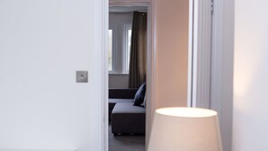 A hotel room with a bed, a bedside table, and a lamp.