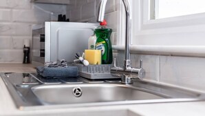 A modern kitchen with a stainless steel sink, a dish soap bottle, a sponge, and a dish rack.