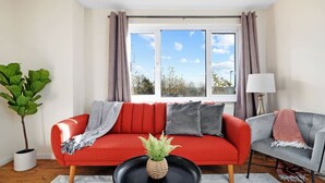 Ein modernes Wohnzimmer mit einem roten Sofa, einem grauen Sessel und einem schwarzen Couchtisch mit einer Pflanze.