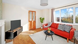 Ein modernes Wohnzimmer mit großem Fenster, einem roten Sofa, einem Fernseher und einem Kamin.