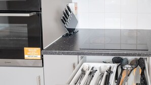 A kitchen with a black countertop, a knife block, and a drawer with utensils. - The Ipswich Snug Spacious 3BR Retreat FREE Parking (Ipswich)