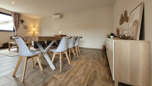 Een moderne eetruimte met een houten tafel, vier grijze stoelen en een lichtkleurige kast.
