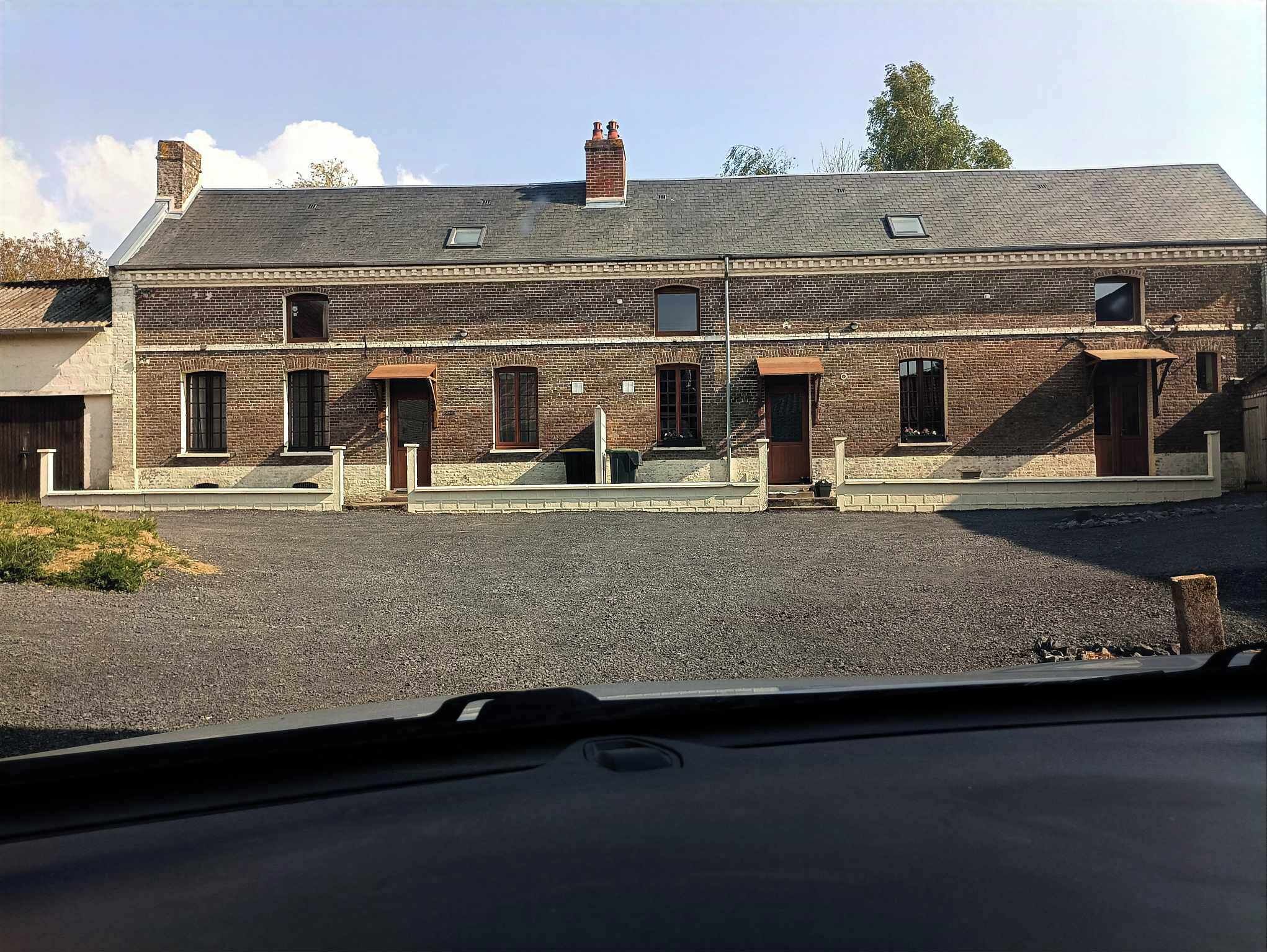 En toetages murbygning med fladt tag, flere vinduer og en grusbelagt indkørsel.