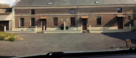 En toetages murbygning med fladt tag, flere vinduer og en grusbelagt indkørsel.