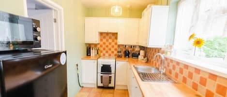 Enjoy cooking in this kitchen with a refrigerator, oven, and microwave. A sink with a faucet and window with a view complete the space.