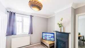 Una sala de estar moderna con chimenea, televisor y ventana con cortinas.