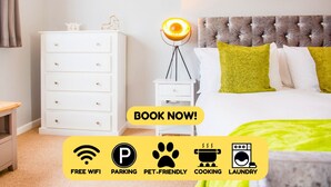 Habitación de hotel con cama, mesita de noche, lámpara y cómoda. Incluye wifi gratuito, estacionamiento, admite mascotas, cocina y servicio de lavandería.