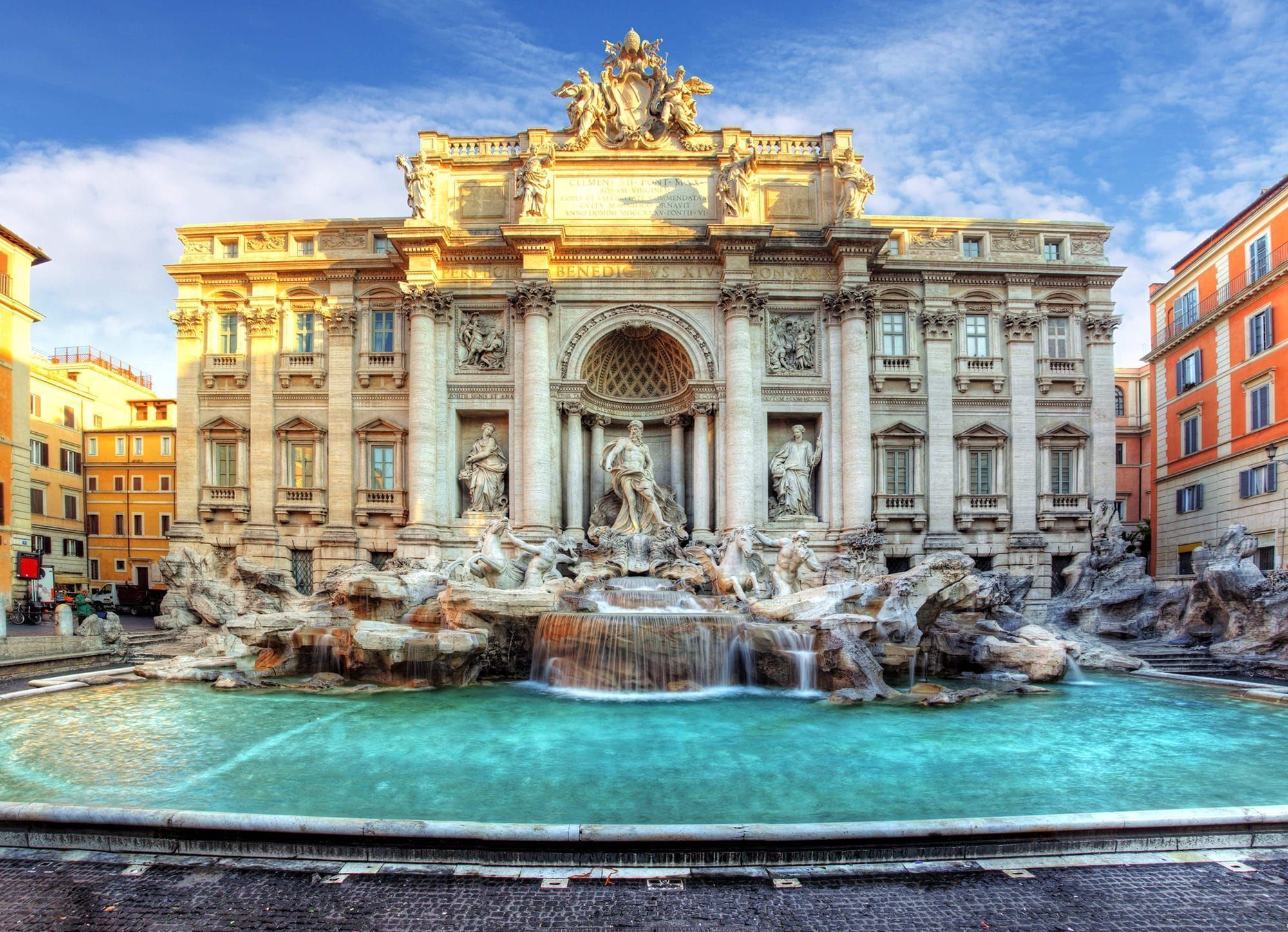A grand building with a large fountain in front, featuring statues and intricate architecture.