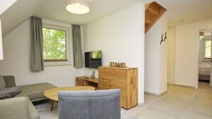 Una sala de estar moderna con un sofá, una mesa de centro, un armario de madera y un televisor.