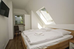 A bedroom with a large bed, a desk, a chair, and a TV. - Beachfront apartment with balcony, use of swimming pool and sauna - Rex Rugia apartment 17-5 - (Göhren)