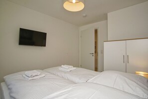 A hotel room with two beds, a television on the wall, and a wardrobe. - Beachfront vacation rental with a balcony, pool access, and a sauna - Rex Rugia - Rex Rugia (Göhren)