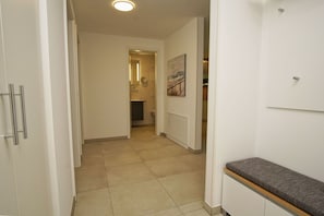 A hallway with a tiled floor, a door with a handle, and a painting on the wall. - Beachfront vacation rental with a balcony, access to the pool and sauna - Rex Rugia - Rex Rugia (Göhren)