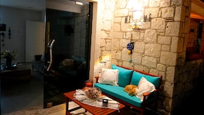 A cozy living room with a sofa, a coffee table, and a stone wall. - Kiva Alaçatı Hotel By Amarillo  (Cesme)