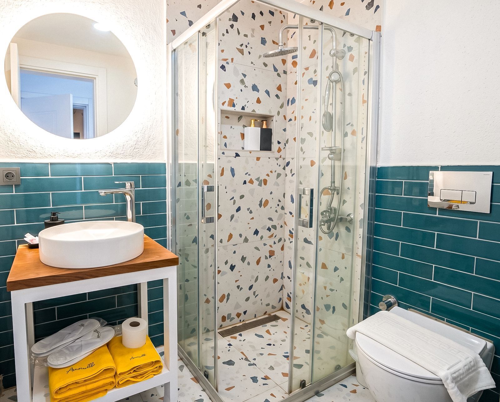 A bathroom with a glass-enclosed shower, a sink with a wooden countertop, and a toilet.